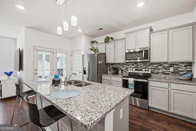 kitchen featuring appliances with stainless steel finishes, sink, pendant lighting, and a kitchen island with sink