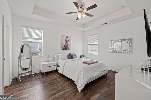 bedroom featuring dark hardwood / wood-style flooring, a raised ceiling, and ceiling fan