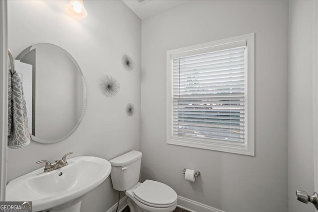 bathroom featuring toilet, sink, and a wealth of natural light