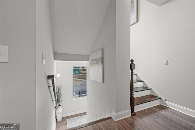 stairway with wood-type flooring and lofted ceiling