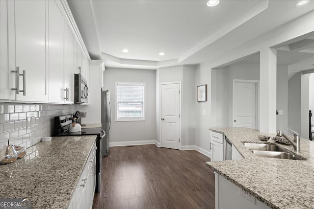 kitchen featuring appliances with stainless steel finishes, sink, white cabinets, light stone counters, and a raised ceiling