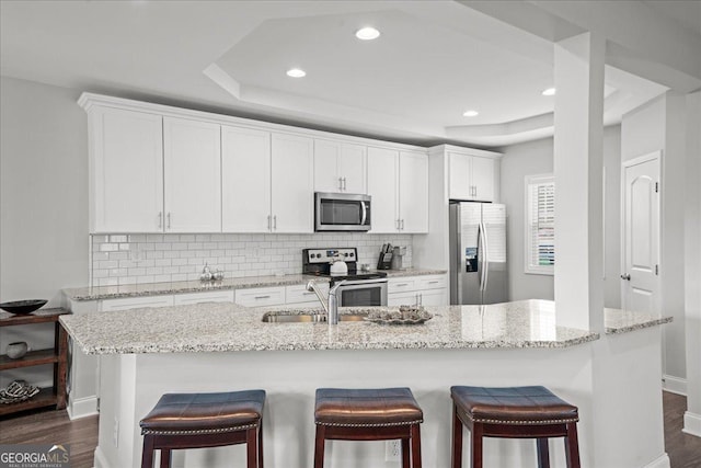 kitchen with stainless steel appliances, a center island with sink, and white cabinets