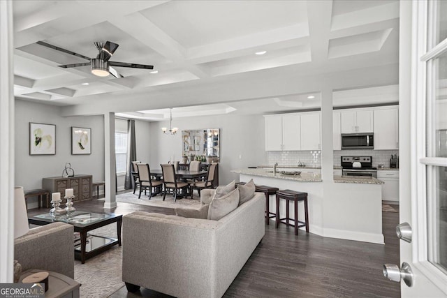 living room with dark hardwood / wood-style flooring, beam ceiling, coffered ceiling, and a chandelier