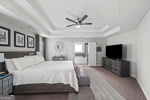 carpeted bedroom featuring a raised ceiling, ceiling fan, and ensuite bath