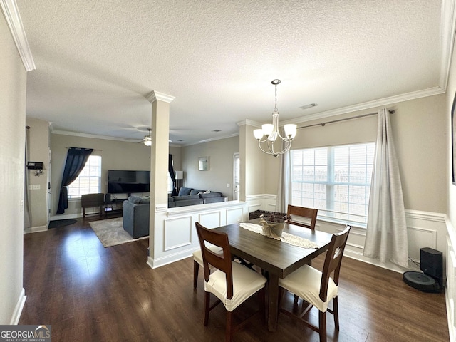 dining area with dark wood-type flooring, ornate columns, crown molding, a textured ceiling, and ceiling fan with notable chandelier