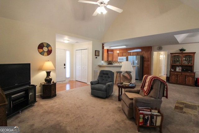 carpeted living room with high vaulted ceiling and ceiling fan