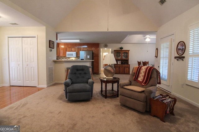 living room featuring ceiling fan, light colored carpet, and high vaulted ceiling