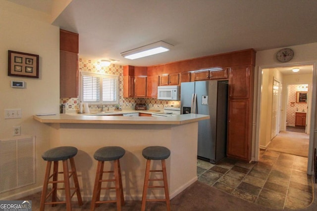 kitchen with sink, stainless steel fridge, a breakfast bar area, range, and kitchen peninsula