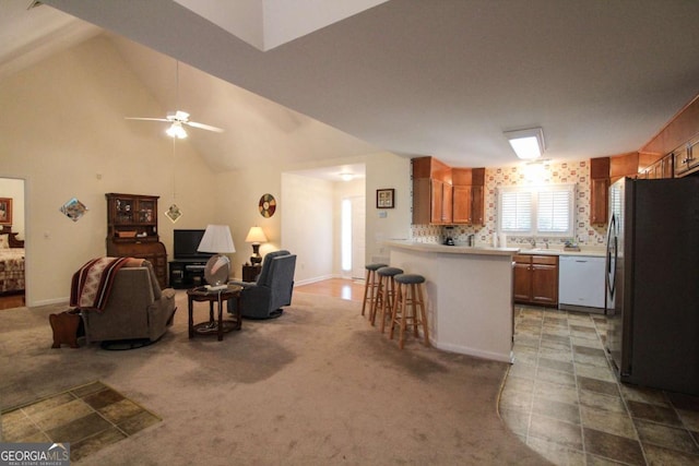 kitchen with black refrigerator, dishwasher, carpet flooring, a kitchen bar, and kitchen peninsula