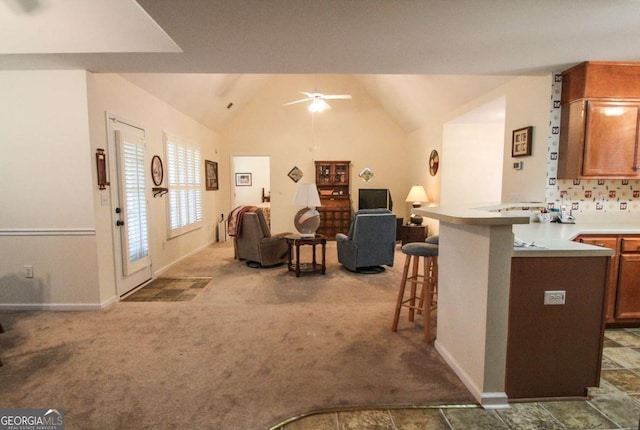 kitchen with a breakfast bar, high vaulted ceiling, carpet floors, ceiling fan, and kitchen peninsula