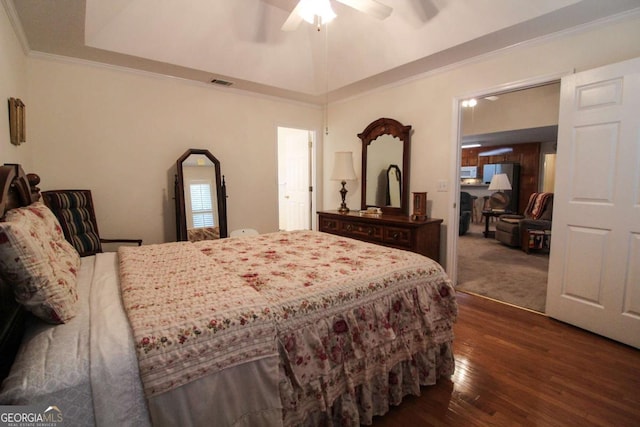 bedroom with dark wood-type flooring, vaulted ceiling, ornamental molding, a raised ceiling, and ceiling fan