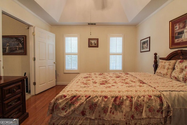 bedroom with ornamental molding, dark hardwood / wood-style flooring, and a raised ceiling