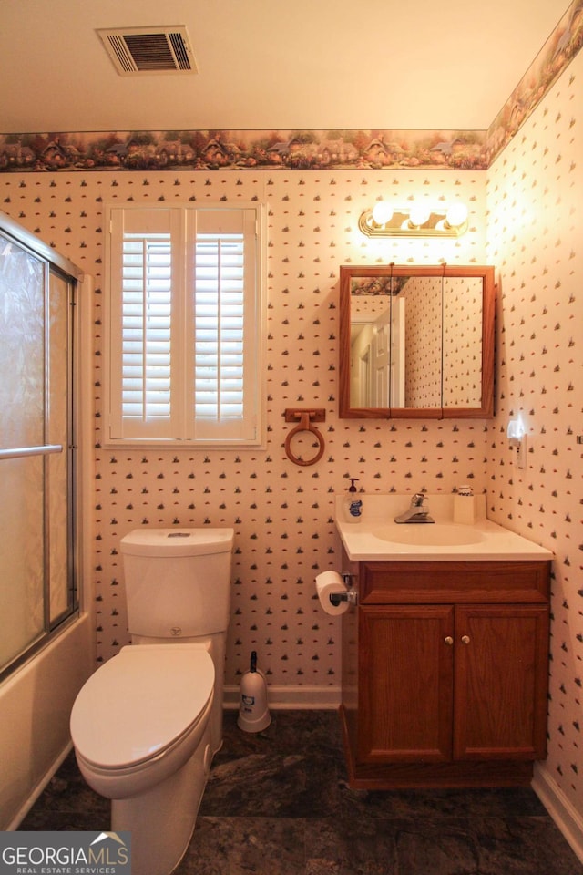 full bathroom with toilet, vanity, and bath / shower combo with glass door