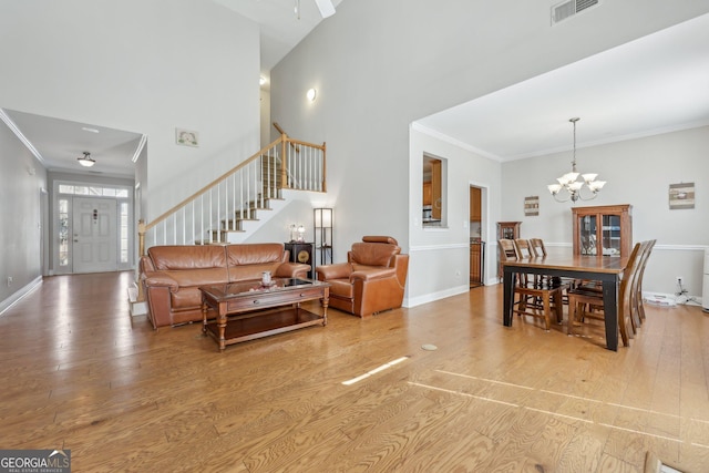 living room with an inviting chandelier, ornamental molding, and light hardwood / wood-style flooring