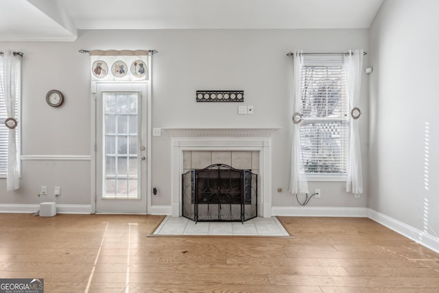 unfurnished living room with a tiled fireplace and light hardwood / wood-style flooring