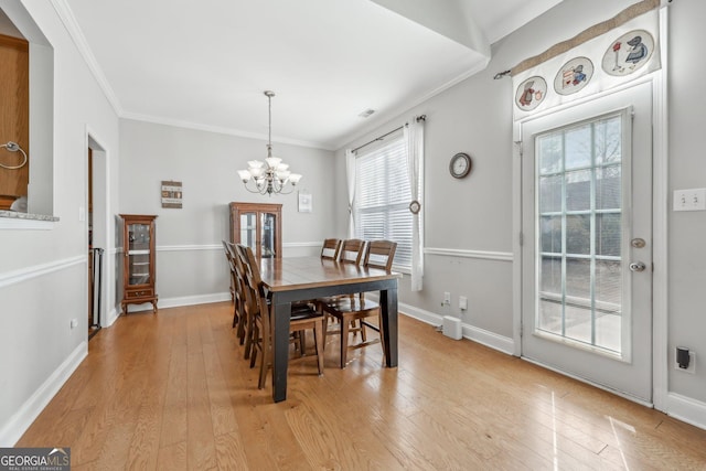 dining space featuring an inviting chandelier, ornamental molding, and light hardwood / wood-style flooring