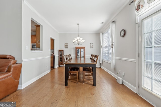 dining area featuring crown molding, an inviting chandelier, and light wood-type flooring