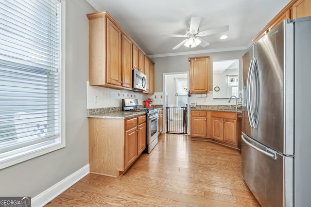 kitchen featuring crown molding, light hardwood / wood-style flooring, appliances with stainless steel finishes, light stone counters, and a healthy amount of sunlight