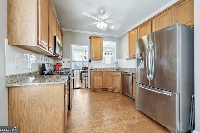 kitchen with stainless steel appliances, ornamental molding, light stone countertops, and light wood-type flooring