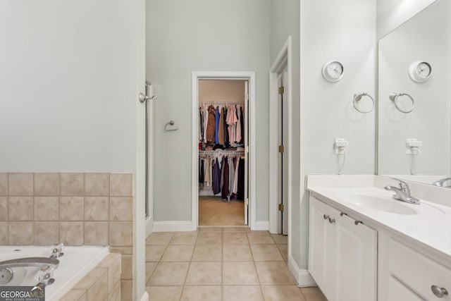 bathroom featuring tile patterned flooring, vanity, and a relaxing tiled tub