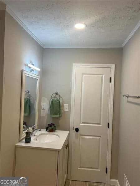 bathroom with vanity, ornamental molding, and a textured ceiling