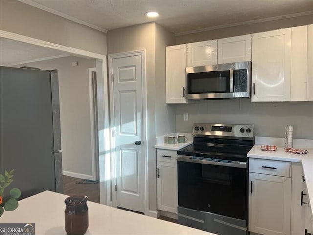 kitchen featuring white cabinetry, dark wood-type flooring, ornamental molding, and stainless steel appliances