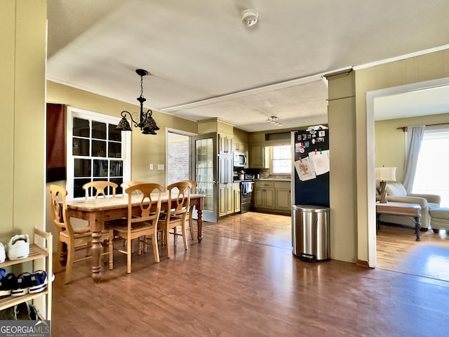 dining space featuring hardwood / wood-style flooring, ornamental molding, and a notable chandelier