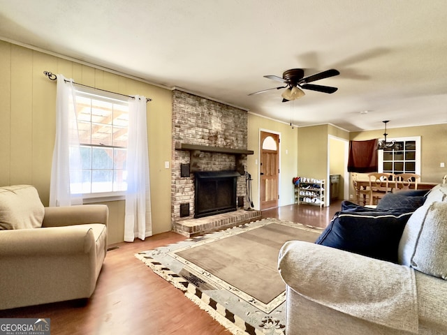 living room featuring a brick fireplace, crown molding, light hardwood / wood-style flooring, and ceiling fan