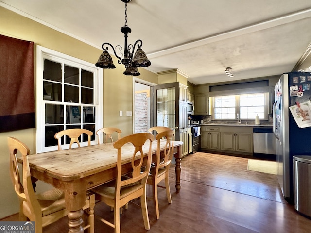 dining space featuring hardwood / wood-style flooring, ornamental molding, sink, and a chandelier