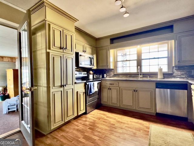 kitchen with ornamental molding, appliances with stainless steel finishes, sink, and backsplash