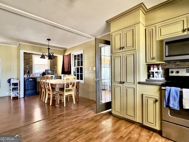 kitchen featuring ornamental molding, appliances with stainless steel finishes, light wood-type flooring, and cream cabinets