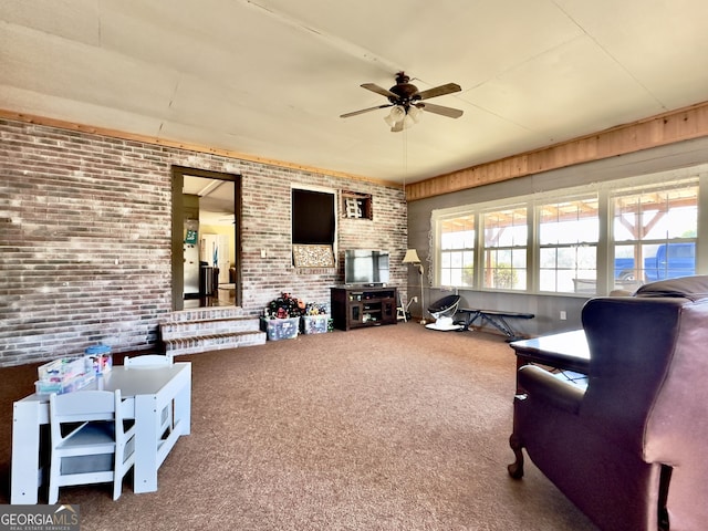 carpeted living room featuring ceiling fan and brick wall