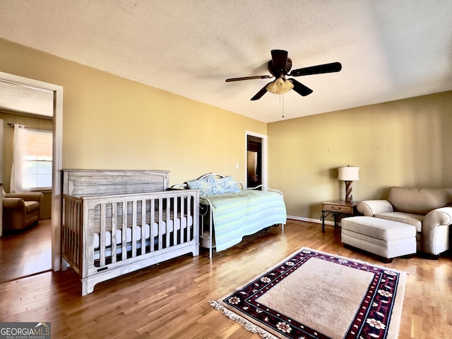 bedroom featuring ceiling fan, wood-type flooring, and a textured ceiling