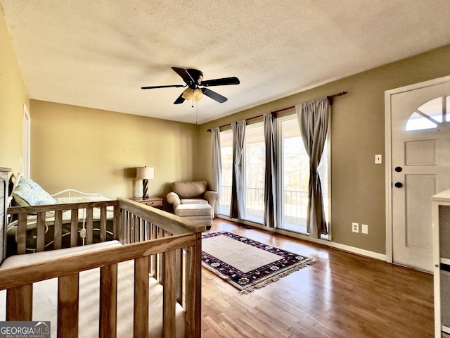 bedroom featuring ceiling fan, hardwood / wood-style floors, and a textured ceiling