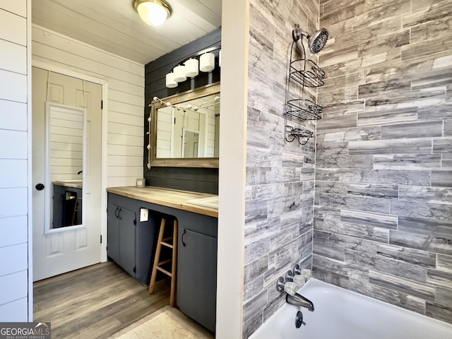 bathroom with tiled shower / bath, vanity, and wood-type flooring