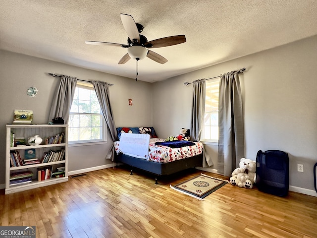 bedroom featuring ceiling fan, hardwood / wood-style floors, and a textured ceiling