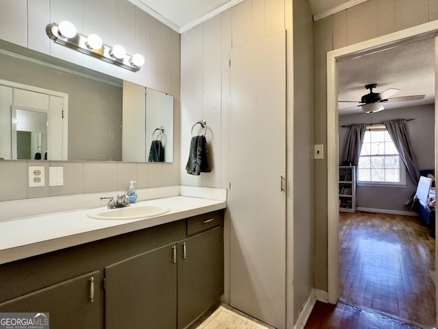 bathroom with hardwood / wood-style flooring, ceiling fan, vanity, ornamental molding, and wood walls