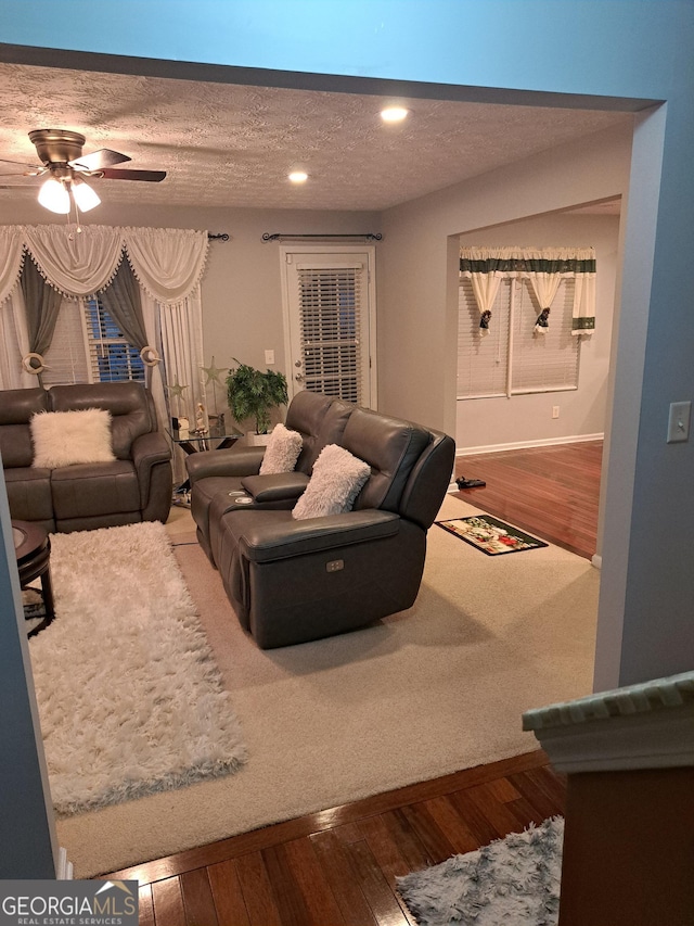 living area featuring recessed lighting, hardwood / wood-style floors, a ceiling fan, a textured ceiling, and baseboards