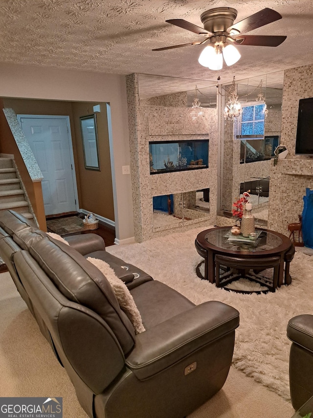 carpeted living room with ceiling fan, a textured ceiling, and baseboards