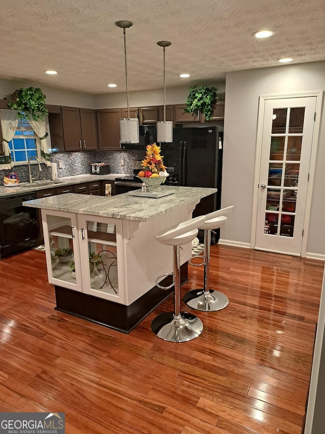 1440 Steam Engine Way NE, Conyers, GA 30013 - kitchen featuring black appliances, decorative backsplash, wood finished floors, a textured ceiling, and a kitchen island