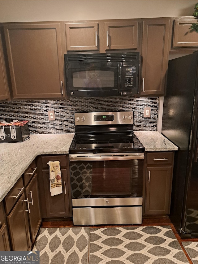 kitchen with black appliances, light stone countertops, and decorative backsplash