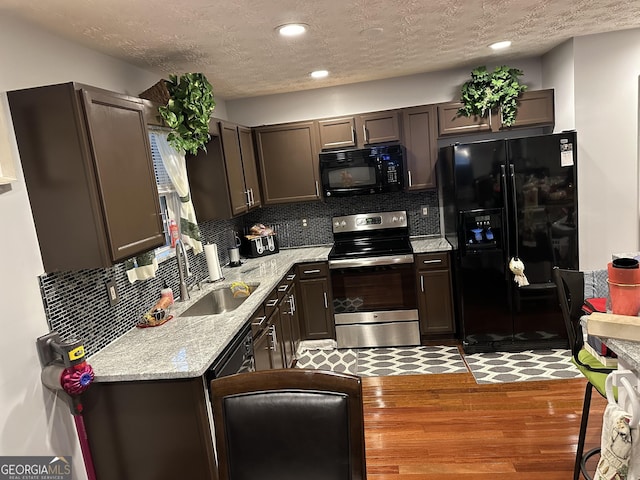 kitchen featuring a textured ceiling, black appliances, wood finished floors, and decorative backsplash