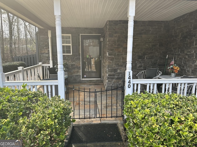 doorway to property featuring covered porch and fence