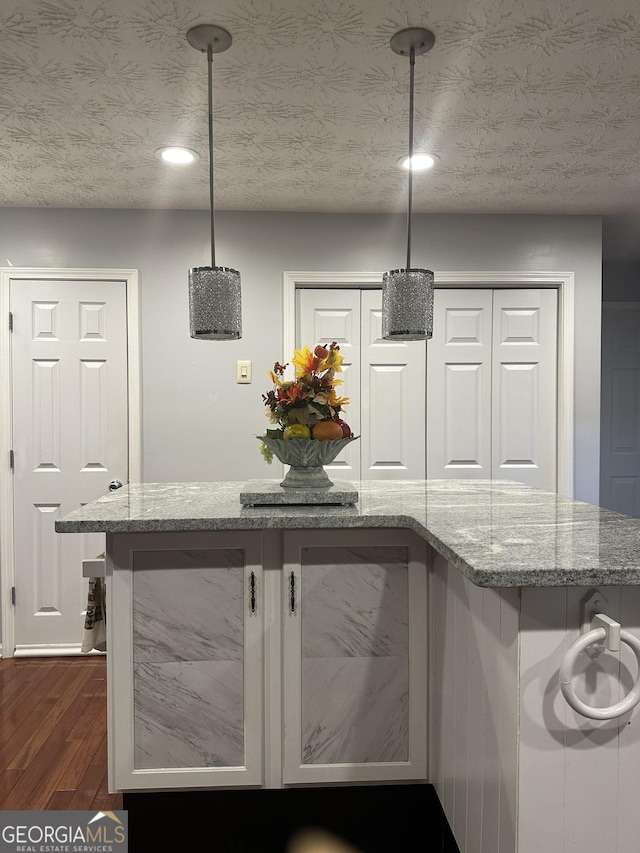 kitchen with recessed lighting, dark wood finished floors, a textured ceiling, and light stone countertops