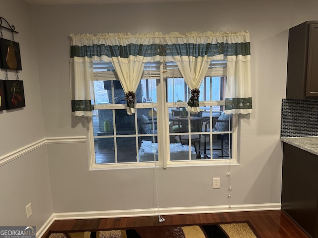 unfurnished dining area featuring wood finished floors and baseboards