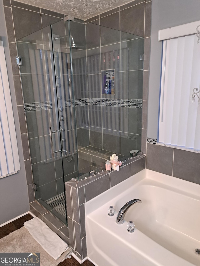 bathroom with a garden tub, a shower stall, and wood finished floors