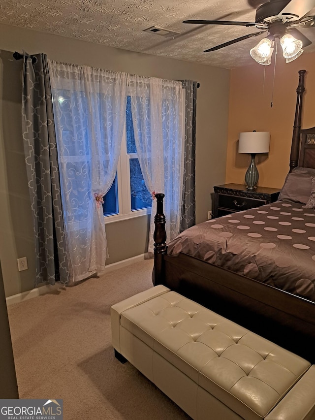 carpeted bedroom featuring visible vents, ceiling fan, and a textured ceiling