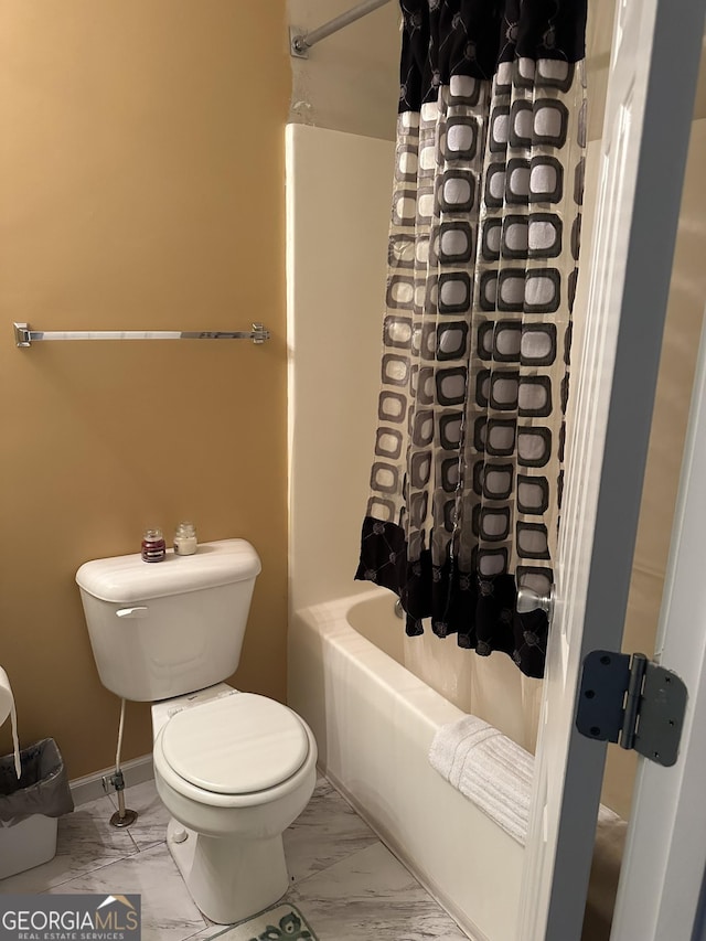 bathroom with toilet, marble finish floor, baseboards, and shower / tub combo