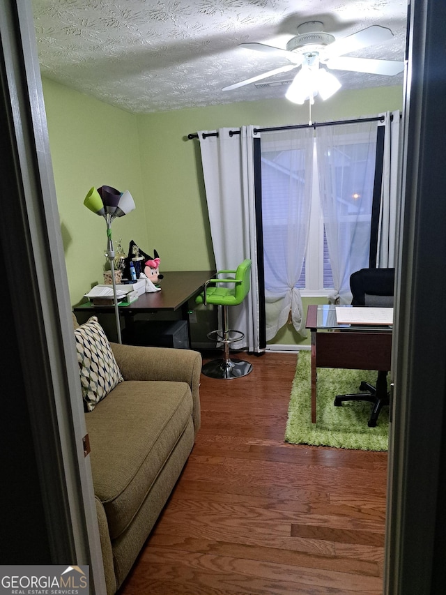 home office with a textured ceiling, wood finished floors, and a ceiling fan