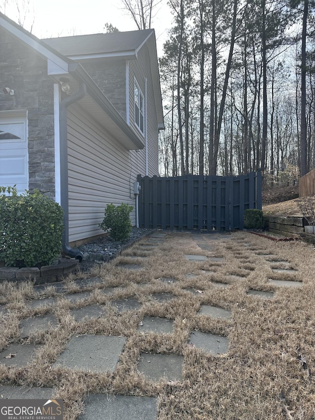 view of property exterior featuring stone siding and fence